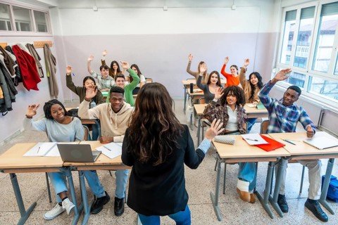 Multi ethnic university students enthusiastically raising hands to respond to the teacher's