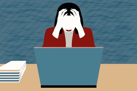 A businesswoman sits at her desk, visibly stressed and frustrated with her laptop in front of her.