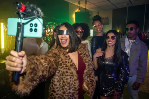Diverse group of young adults enjoying a night out, capturing fun content with a smartphone on a
