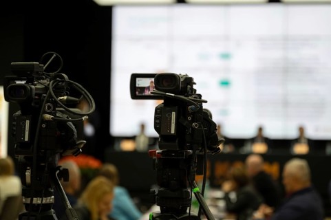 Camera during press conference with speaker in the background in Lubin, Poland