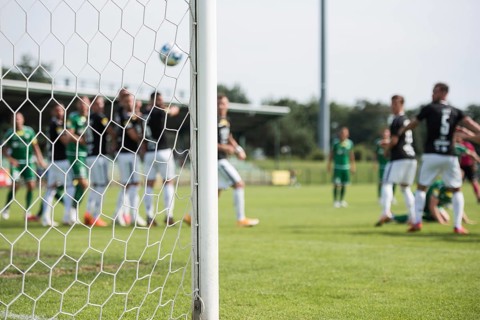 Detail of goal's post with net and football players during free kick in the background in Lubin,