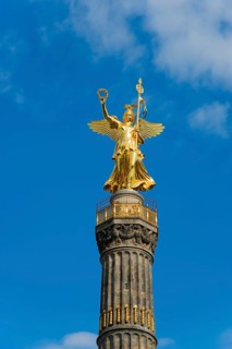 Close-up of the golden figure on the Berlin Victory Column against a blue sky, gilded bronze