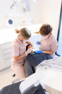 Dentist and assistant performing a mouth and teeth checkup on a young client in the modern dental