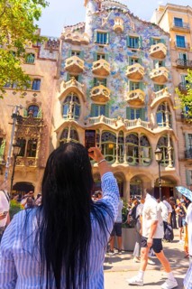 Tourist taking a picture of the colorful facade of casa batllo, a unesco world heritage site in