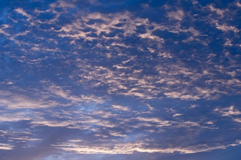 A serene evening sky filled with soft, wispy clouds illuminated by gentle twilight hues. The sky
