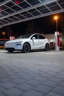White electric car at a charging station under a covered area at night, Tesla, Leonberg, Germany