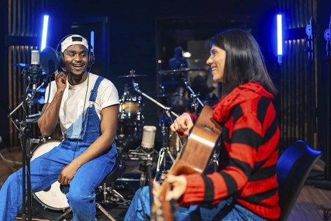 Two musicians playing guitar and singing, recording a new hit song in a professional recording