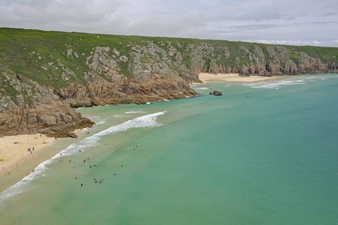 Wunderschöner Sandstrand an türkisfarbenem Meer mit umgebenden Klippen, Porthcurno, St Levan,