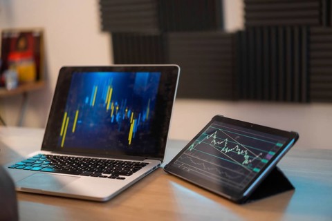 Home office with a laptop with gaphs of data of investment trading on crypto