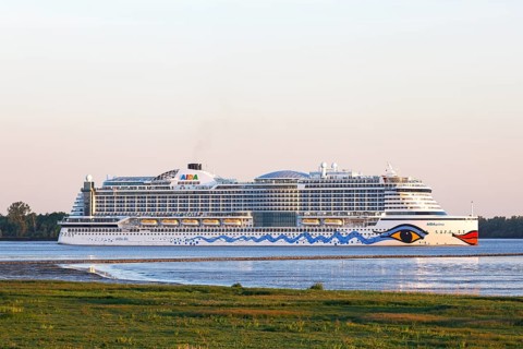 Cruise ship AIDA Prima leaving the harbour of Hamburg on the river Elbe in the evening light,