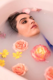 Artistic portrait from above of a relaxed model taking a milk bath with flowers