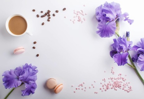 Purple iris flowers and a cup of coffee on a white background. Morninig, spring, fashion