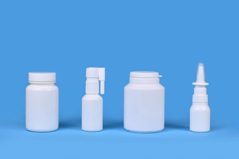 Medication for cold and flue. Nasal spray, throat spray, pills in a row on blue background