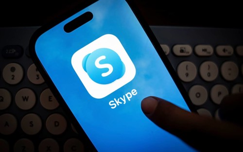 In this photo illustration, a person holds a mobile phone displaying Skype application, in