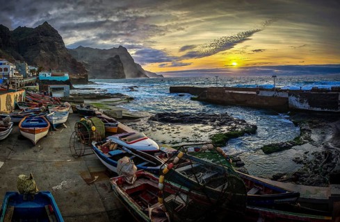 Sunset over a coastal landscape with colorful fishing boats and mountains, graffiti, romantic