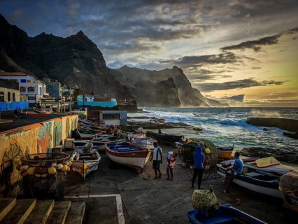 Four people at the harbor in front of dramatic light fishing net and colorful boats on the coast