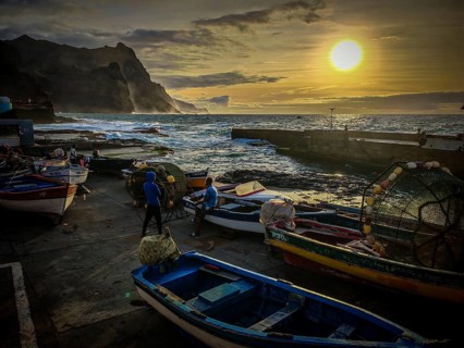 Fishing net, fishermen and colorful boats on the coast with a quiet evening mood at the fishing