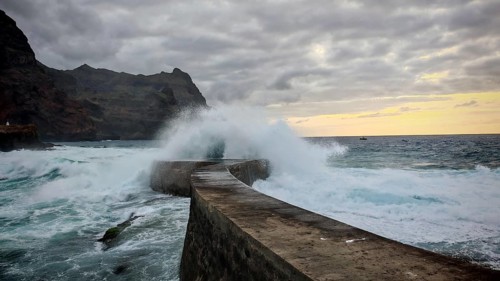 Dramatic waves hit a pier surrounded by rocks and a cloudy sky, Ponta do Sol, Santo Antao, Cabo