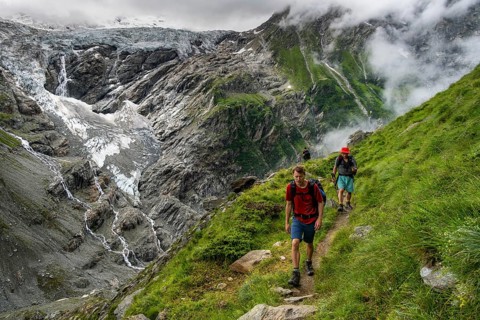 Two mountaineers on a hiking trail, cloudy mountain landscape with Grindelwald-Fiescherfirn