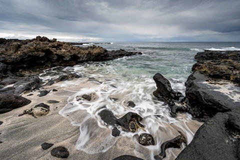Waves blaze on the beach, rocky coast with volcanic stones, long exposure, Playa de la Pequeña,