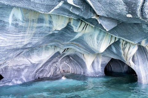 Marble caves (Cuevas de Mármol) with blue and white veined rock formations over turquoise-coloured