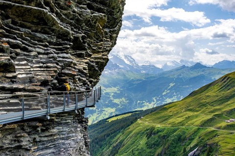 Young man on First Cliff Walk, metal trail on a rocky outcrop, Grindelwald First, in front of