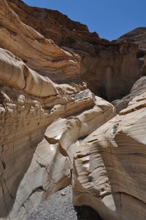 Narrow, layered rock walls form a narrow passage of a hiking trail in the desert, Death Valley