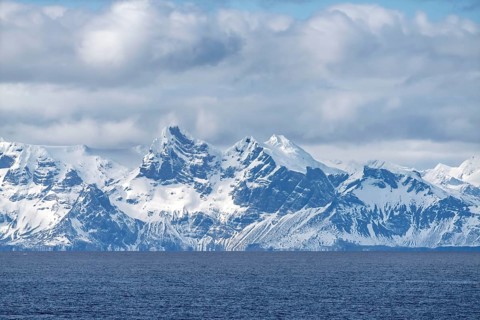 Snow-capped mountain range with rugged peaks, cloudy skies, coast of South Georgia, South Georgia
