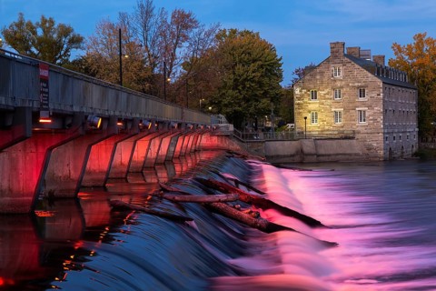 Illuminated Moulin Neuf water flow control dam and walkway over Des Mille-Iles river plus New Mill