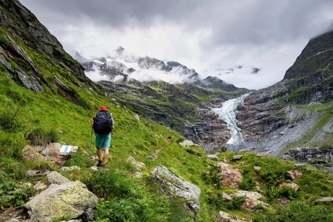 Mountaineers on a hiking trail, cloudy mountain landscape with Lower Arctic Sea glacier, Bernese