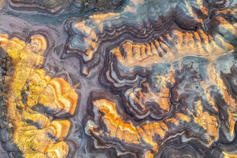 Aerial view of striking golden bentonite formations in Utah, USA. The layered textures and vibrant