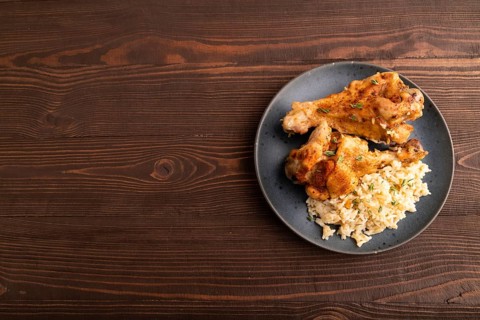 Fried Turkey Wing with spices and rice on plate on brown wooden background. top view, flat lay,