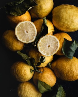 A vibrant display of fresh, bright yellow lemons complemented by contrasting green leaves. The
