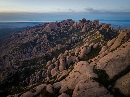 Aerial view of dramatic rock formations in Montserrat, Catalonia, at sunset. The rugged landscape