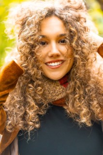 Close-up of a beauty woman with curly hair outdoors in a park with golden colors in the leaves