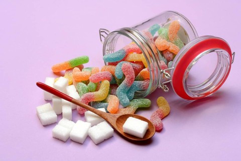 Lots of colorful jelly sweets in glass containers and sugar cubes, sugar consumption