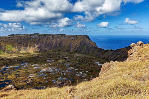 View from the crater rim of the vast crater and the sea behind it under a blue sky, the Ranu Kau
