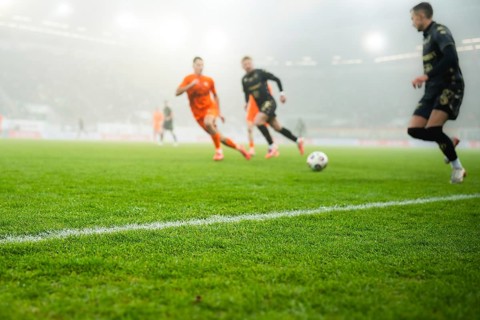 Grass and sideline on the football pitch at the stadium and player's legs at the background in