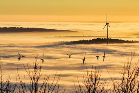 Forest and wind turbines rise from cloud cover, wind farm, silhouettes at sunset, dense sea of fog