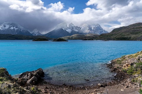 Turquoise Lake Pehoé with small islands, in the background the cloud-shrouded Cuernos del Paine,