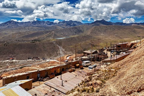 Wide mountain landscape with cloudy sky and small huts in the foreground, The silver mines of