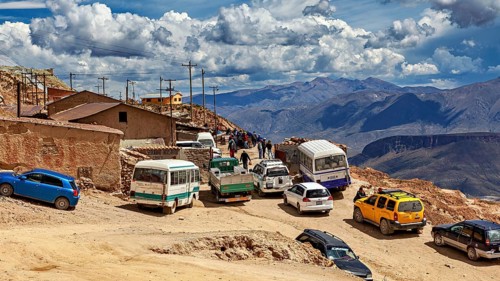 Series of vehicles on a winding road in a mountainous region under a blue sky, The silver mines of