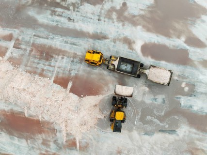Excavator and lorry at a harvesting pan of the Walvis Bay Salt works. Aerial view. Drone shot.