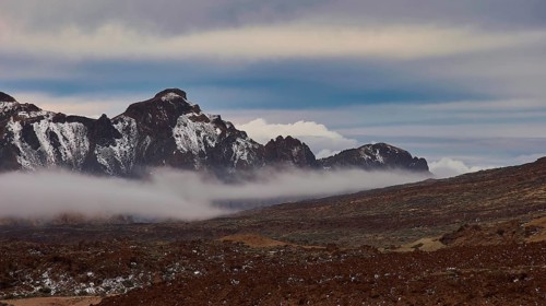Caldera, mountain landscape with clouds, fog and snowy peaks under a blue sky, Teide, Parque