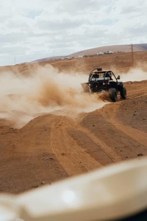 A thrilling off-road vehicle navigating the dusty, rugged terrain of Lanzarote, with rolling hills
