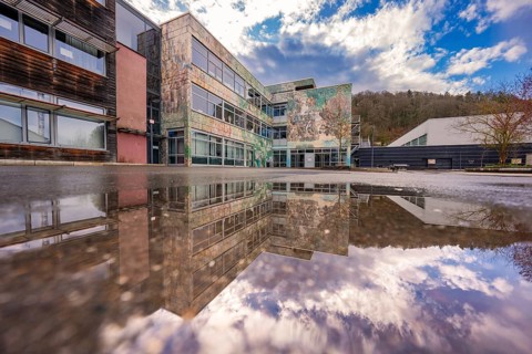 Modern building reflected in a water surface under a dramatic sky, Nagold, Calw district, Germany