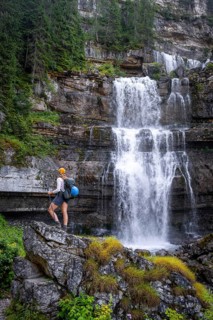 Young pretty hiker standing on rocks in front of Cascata di Mezzo waterfall, long exposure,