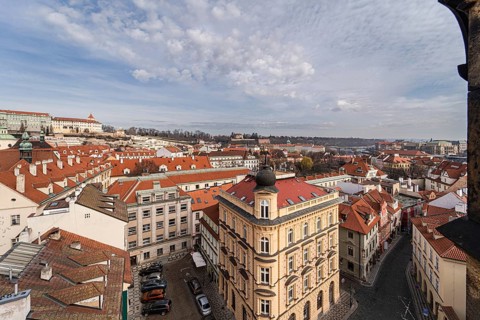 A wide-angle view of Prague's scenic cityscape showing colorful rooftops, historic architecture,