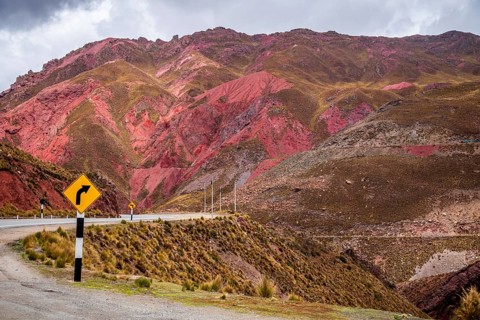 A stunning view of the Peruvian Andes, featuring vibrant red mountain slopes and a winding road