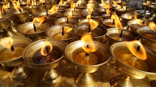 An arrangement of oil lamps with burning flames creates a meditative mood, Bodnath, Kathmandu,